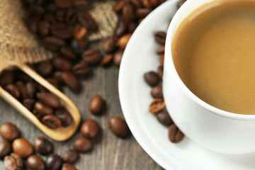 Cup of coffee with beans on table close up