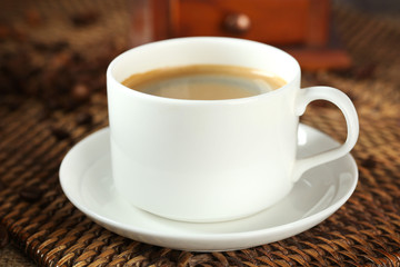 Cup of coffee with beans on table close up