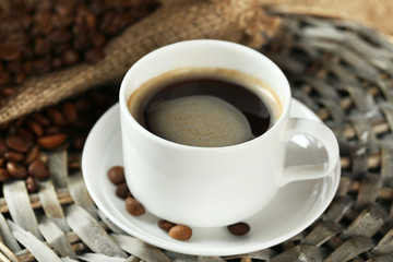 Cup of coffee with beans on table close up