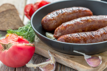 Fried sausage, tomato and garlic closeup.