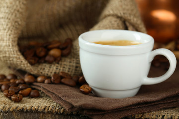 Cup of coffee with beans on table close up