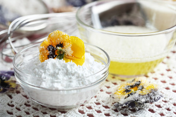 Making candied violet flowers with egg whites and sugar, on color wooden background