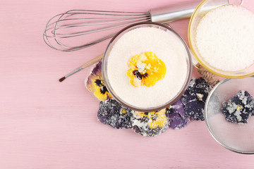 Making candied violet flowers with egg whites and sugar, on color wooden background