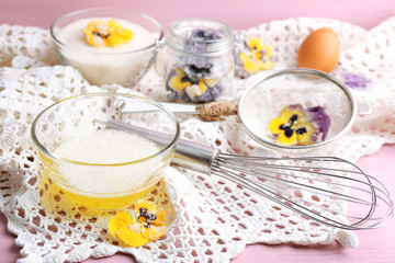 Making candied violet flowers with egg whites and sugar, on color wooden background