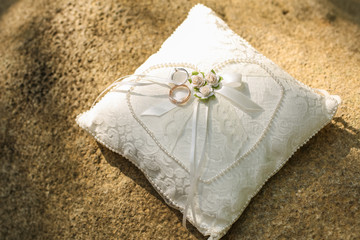 Golden wedding rings on a pillow.