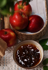 Apple jam and fresh red apples on wooden table close-up