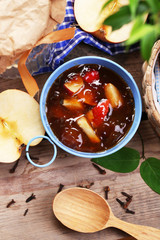 Apple jam in pail and fresh red apples on wooden table close-up