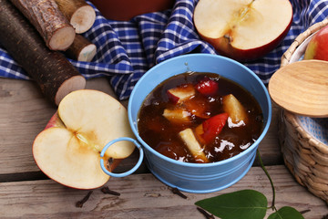 Apple jam in pail and fresh red apples on wooden table close-up