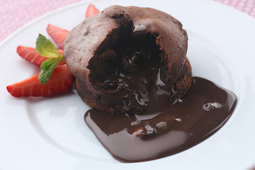 Chocolate fondant with strawberries on white plate, closeup