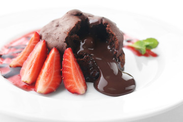 Chocolate fondant with strawberries on white plate, closeup