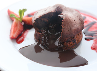 Chocolate fondant with strawberries on white plate, closeup