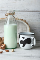 Milk in glassware and walnuts on wooden background