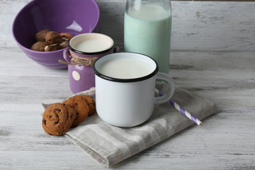Milk in mug with walnuts and cookies on wooden background