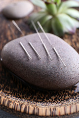 Acupuncture needles with spa stone on tray, closeup