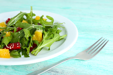 Tasty salad with arugula leaves in plate on wooden table, closeup