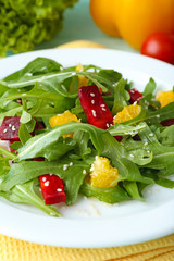 Tasty salad with arugula leaves in plate on wooden table, closeup