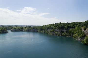 Fototapeta na wymiar Limestone quarry lake with deep blue water and steep walls