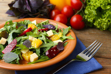 Tasty salad with arugula leaves in plate on wooden table, closeup