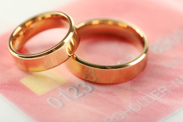 Golden wedding rings and credit card, close up. Marriage of convenience concept