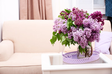 Beautiful lilac flowers in vase on table of interior background