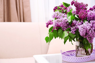 Beautiful lilac flowers in vase on table of interior background