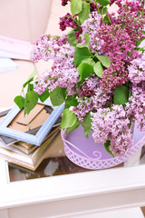 Beautiful lilac flowers in vase on table of interior background
