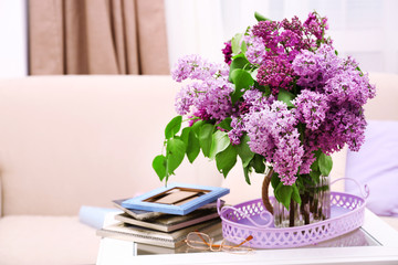 Beautiful lilac flowers in vase on table of interior background