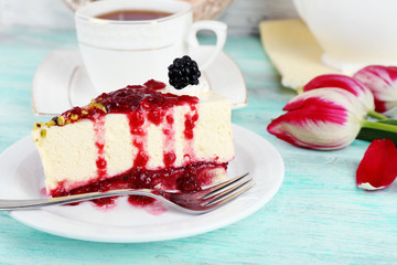 Tasty piece of cheesecake with berry sauce on plate on table close up