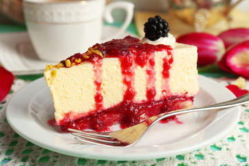 Tasty piece of cheesecake with berry sauce on plate on table close up