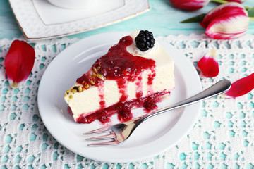 Tasty piece of cheesecake with berry sauce on plate on table close up