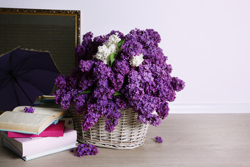 Beautiful lilac flowers in basket on floor in room close-up