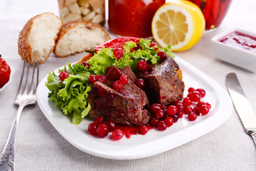 Tasty roasted meat with cranberry sauce on plate, on light background