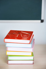Heap of books and glasses on table in class