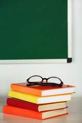 Heap of books and glasses on table in class