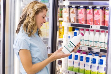 Smiling woman looking at a milk bottle 