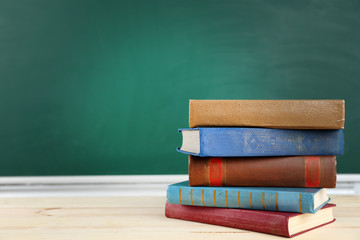 Stack of books on desk, on blackboard background