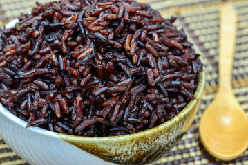 Close up rice berry in bowl with wooden spoon.