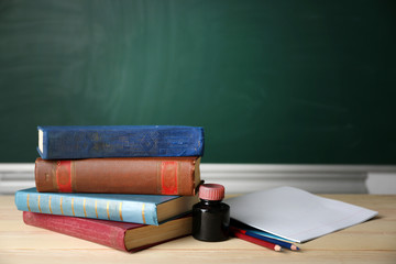 Stack of books on desk, on blackboard background