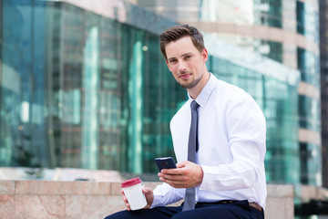 Young Businessman sitting with coffee and smartphone at Hong Kon