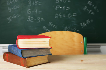 Stack of books on desk, on blackboard background