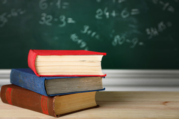 Stack of books on desk, on blackboard background