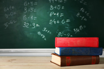 Stack of books on desk, on blackboard background