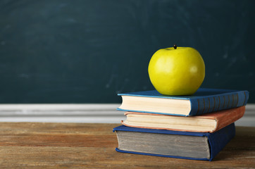 Stack of books on desk, on blackboard background