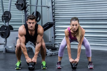 Naklejka premium A muscular couple lifting kettlebells