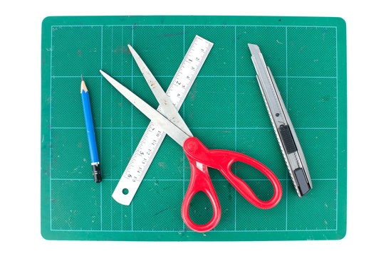 Green cutting mats with scissors ruler pencil and cuter on white