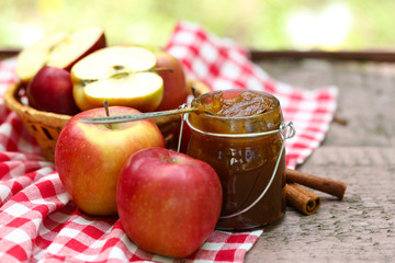 Apple jam in jar and fresh red apples outdoors