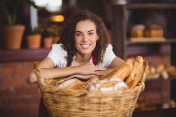 Smiling waitress bended over a basket of bread