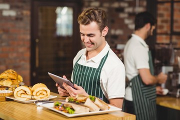 Smiling waiter using a digital tablet
