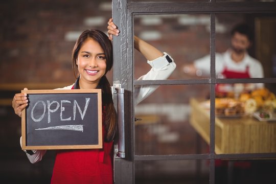 Smiling waitress showing chalkboard with open sign 