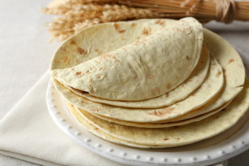 Stack of homemade whole wheat flour tortilla on napkin, on light background